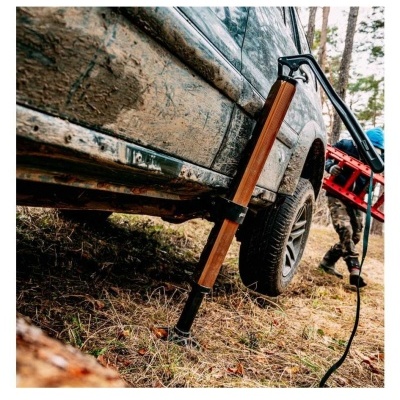 Macaco hidráulico com haste de madeira a levantar veículo fora de estrada sujo