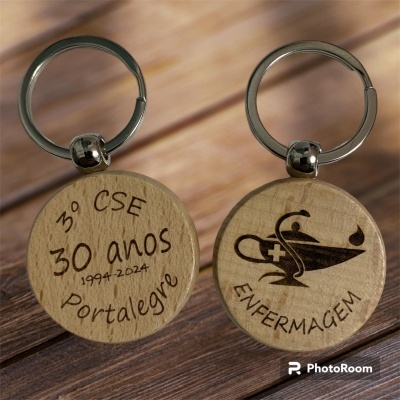 Duas chaves de madeira redondas com gravações a laser, argolas metálicas, texto e símbolo de enfermagem, sobre superfície de madeira.