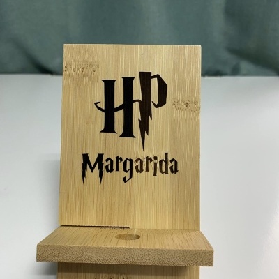 Suporte para telemóvel em madeira clara com letras 'HP' e 'Margarida' em preto.
