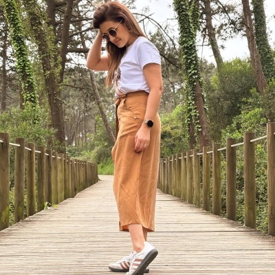 Mulher num passadiço de madeira ao ar livre, vestindo roupa casual