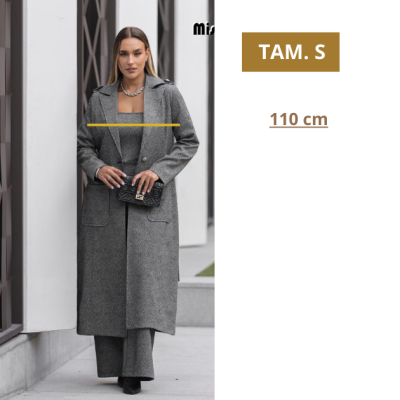 Mulher vestindo casaco cinzento comprido com mala preta e texto TAM. S, 110 cm ao lado.