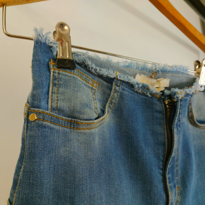 Calças de ganga azuis desfiadas penduradas num cabide