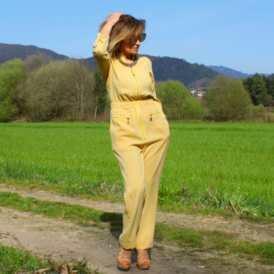 Mulher usando macacão amarelo claro em trilha na natureza