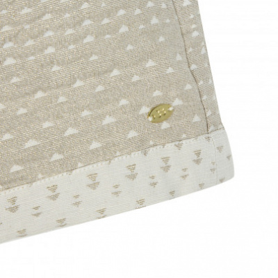 Detalhe de tecido bege com padrão de triângulos e etiqueta metálica dourada 'LOVI'.