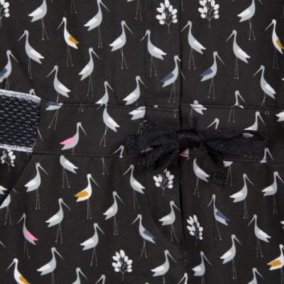 Tecido preto com padrão de pequenas aves coloridas, laço preto e velcro.