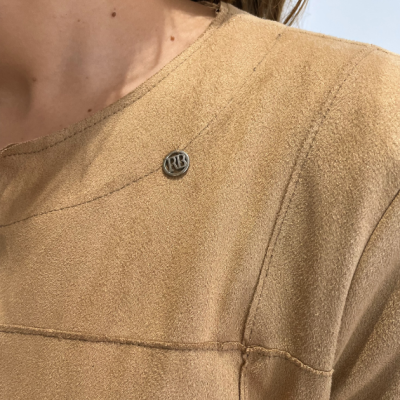 Peça de roupa castanha com textura de camurça e fivela metálica redonda