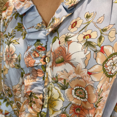 Blusa azul com flores laranja, botões e detalhes franzidos