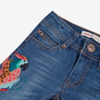 Calças de ganga azul com bordado colorido de papagaio e detalhe de botão metálico