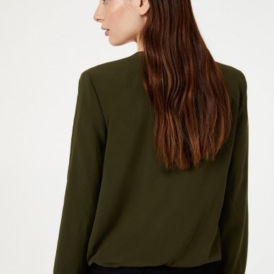 Mulher de costas com blusa verde-oliva e calças pretas
