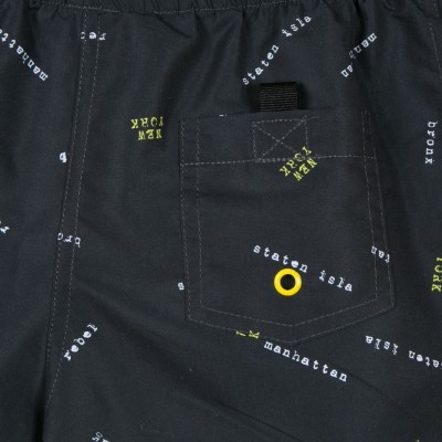 Peça de roupa preta com bolso quadrado, palavras em branco e amarelo, botão amarelo e laço preto