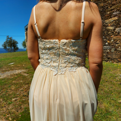 Vestido feminino branco com rendas visto por trás em ambiente exterior