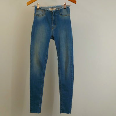 Calças de ganga azuis penduradas num cabide de madeira