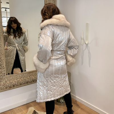 Casaco acolchoado prateado com pele branca junto a espelho