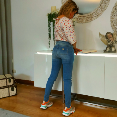 Pessoa de costas com calças de ganga e camisola de pontos, calçando ténis coloridos, num interior decorado