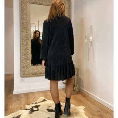 Vestido preto comprido com saia franzida e botas pretas de salto em ambiente interior