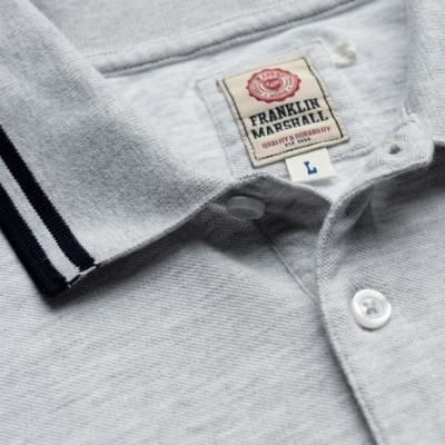 Polo cinzento claro com gola riscada azul escura e etiqueta Franklin Marshall
