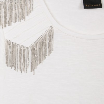 Camisola branca com franjas metálicas prateadas no ombro e etiqueta preta com texto dourado