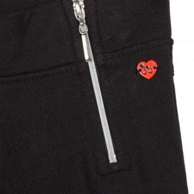 Detalhe de tecido preto com fecho prateado e emblema vermelho em forma de coração