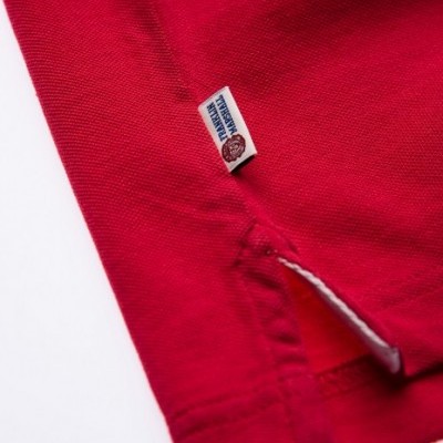 Detalhe de peça de vestuário vermelha com etiqueta 'AUTHENTIC PREMIUM'