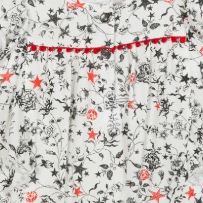 Roupas brancas com padrão de estrelas e flores, pompons vermelhos e botões prateados