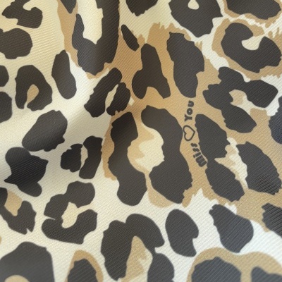 Tecido com estampa animal bege, castanho e preto com texto 'milk you'