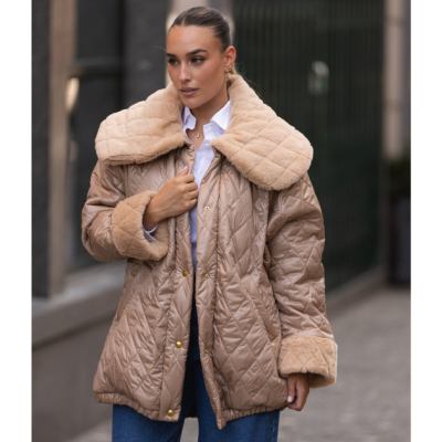 Mulher com casaco acolchoado bege com gola e punhos de pelúcia bege, camisa branca e jeans