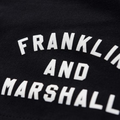 Detalhe de tecido preto com texto impresso branco FRANKLIN AND MARSHALL.