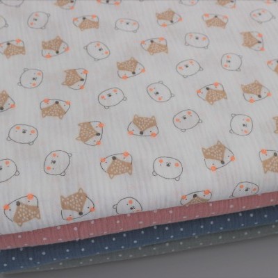 Três tecidos empilhados com padrão de animais e bolinhas.