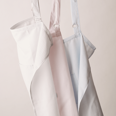 Três aventais de riscas finas em branco, rosa claro e azul claro pendurados