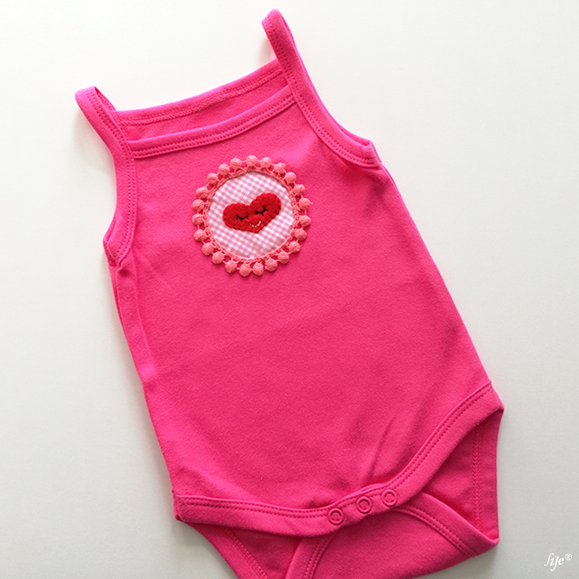 Body de bebê rosa com coração bordado no centro