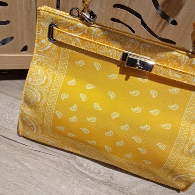 Bolsa amarela com padrão paisley e fecho metálico junto a móvel de madeira clara