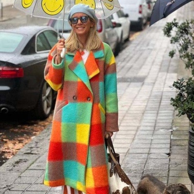 Mulher com casaco colorido em padrão xadrez e guarda-chuva com carinhas sorridentes na rua