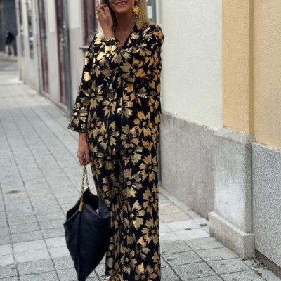 Mulher com conjunto preto e dourado floral e acessórios dourados na rua
