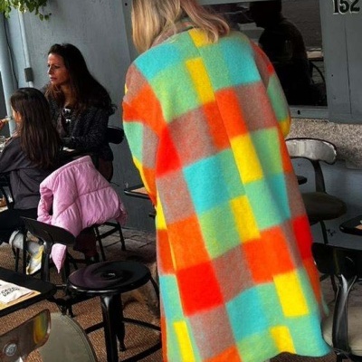 Casaco comprido de padrões geométricos coloridos numa esplanada