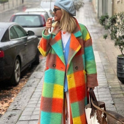 Mulher com casaco xadrez colorido e boina azul segurando guarda-chuva com motivos de sorrisos