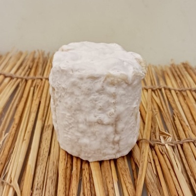 Queijo com crosta branca rugosa sobre palha amarela entrelaçada