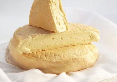 Queijo amarelo pálido com casca rugosa, em duas porções sobre pano branco