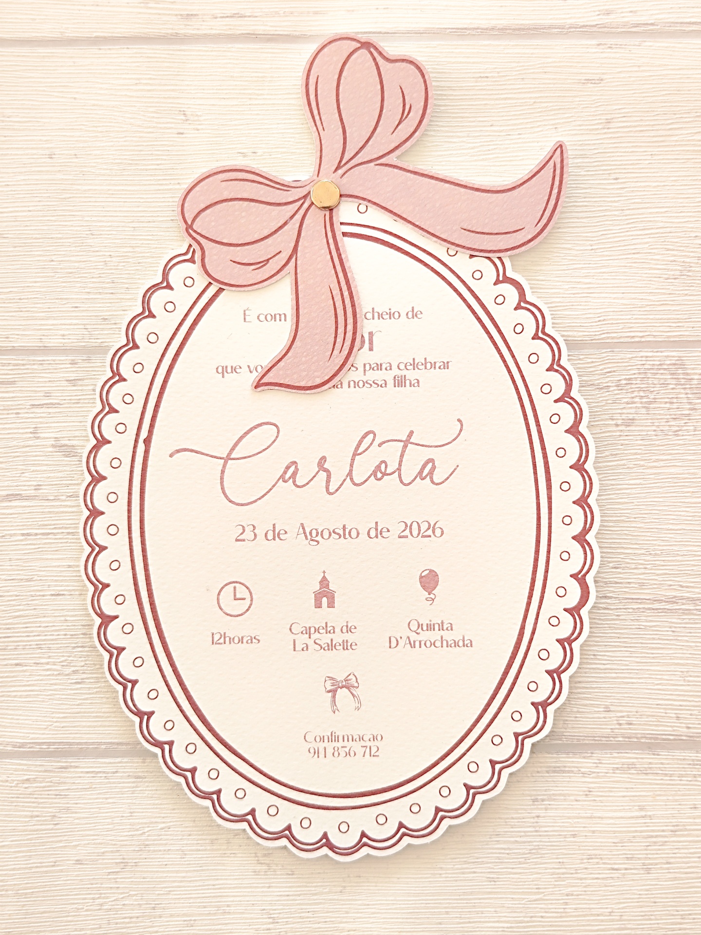 Convite oval com laço rosa e texto em português para evento de Carlota
