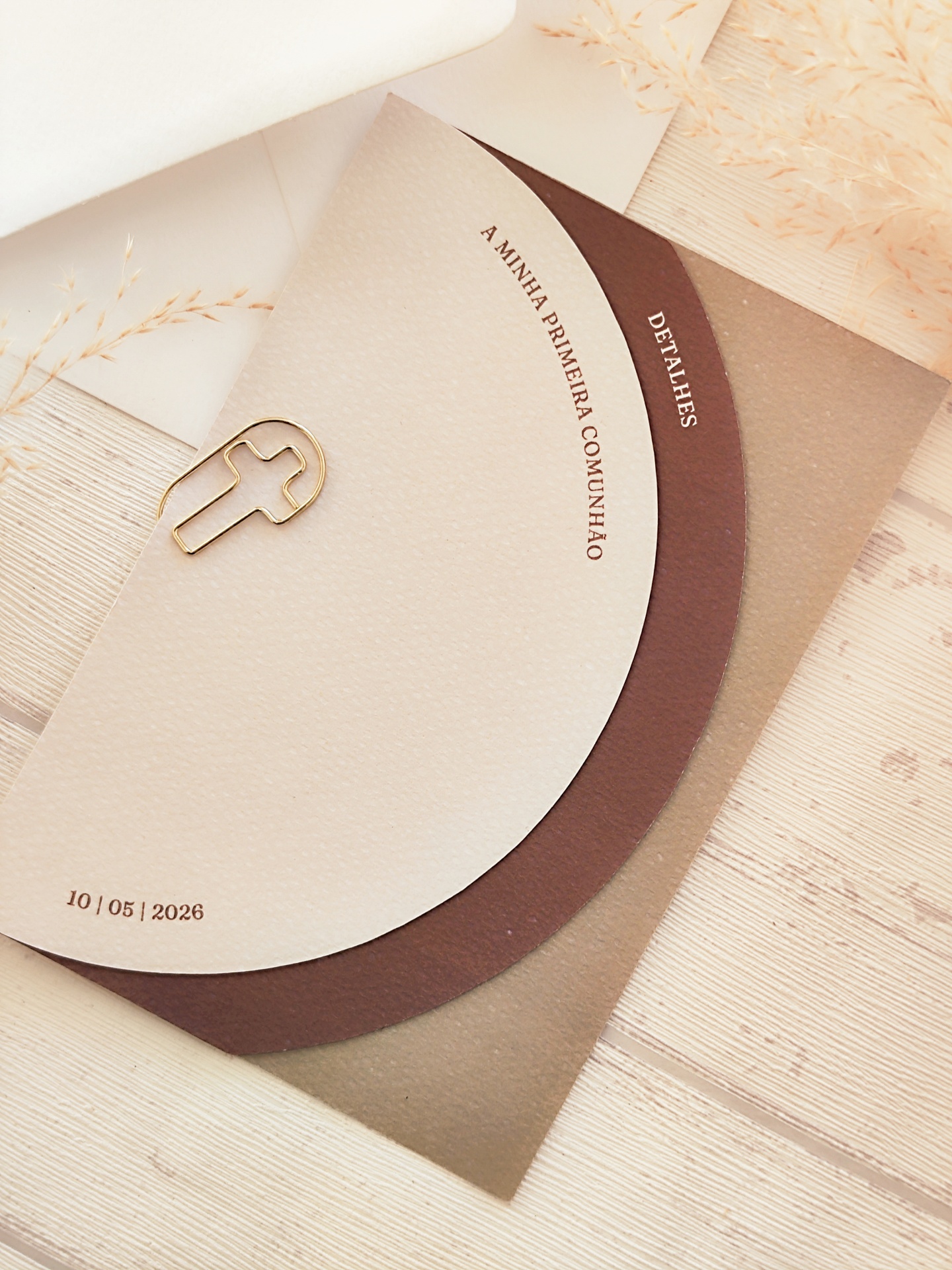 Convite de primeira comunhão redondo em papel castanho e bege com clip dourado em forma de cruz