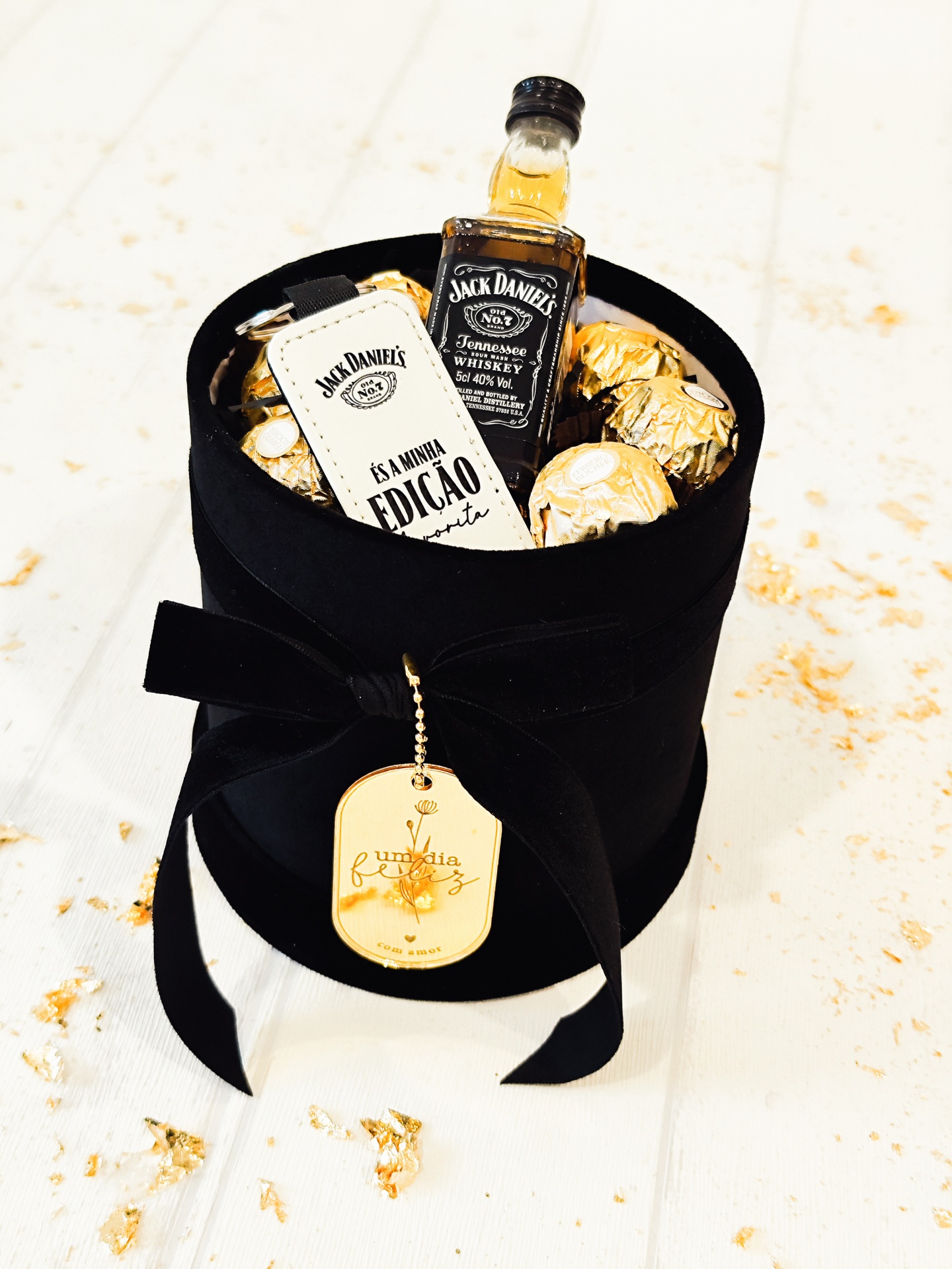 Caixa preta com mini garrafa de Jack Daniels, chocolates dourados e chaveiro branco