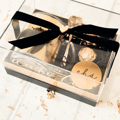 Conjunto presente para chá em caixa transparente com laço preto e medalha em forma de coração.