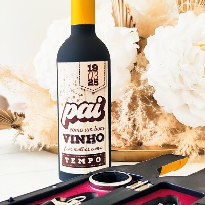 Garrafas de vinho com rótulo personalizado e acessórios para vinho próximos, decorados com flores brancas e sépia.