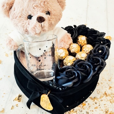 Caixa em forma de coração com ursinho de peluche, copo de vidro, rosas pretas artificiais e bombons dourados