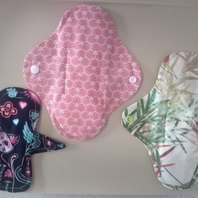 Três pensos reutilizáveis de tecido com diferentes padrões e fechos de pressão