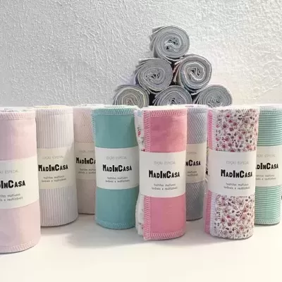 Toalhas multifunções coloridas e estampadas com etiquetas MadInCasa, empilhadas e enroladas