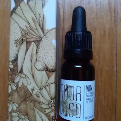 Frasco com conta-gotas e caixa com ilustração botânica sobre madeira