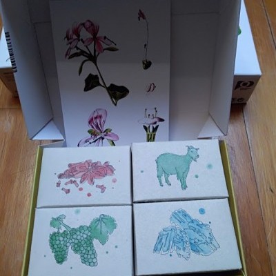 Quatro sabonetes com desenhos coloridos em caixa aberta sobre piso de madeira