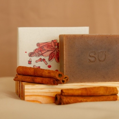 Sabonete marrom com gravação SO, paus de canela e caixa branca com ilustração