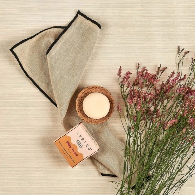 Sabonete com embalagem salmão e flores sobre tecido bege