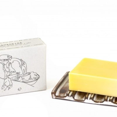 Sabonete amarelo em suporte ao lado de caixa branca com ilustração